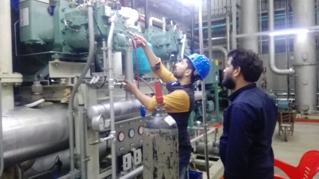 BEC technician in safety helmet testing industrial cooling equipment